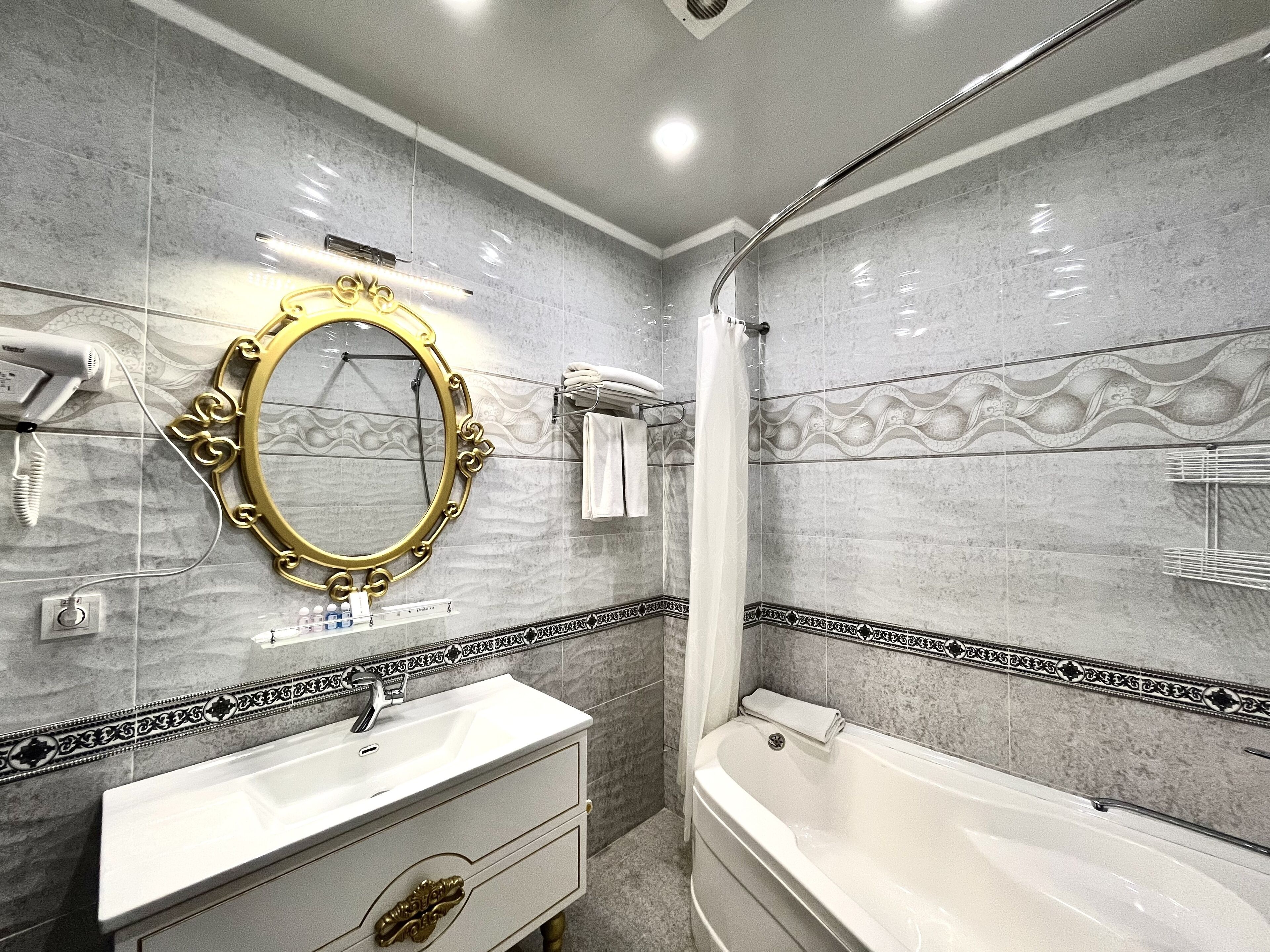 A bathroom with a vanity, sink, mirror, and bathtub.