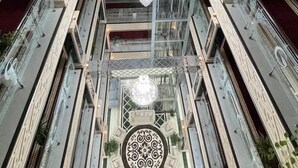 A multi-level atrium with a central chandelier, glass railings, and decorative patterns on the walls and ceiling. - Garden Plaza Bukhara (Bukhara)