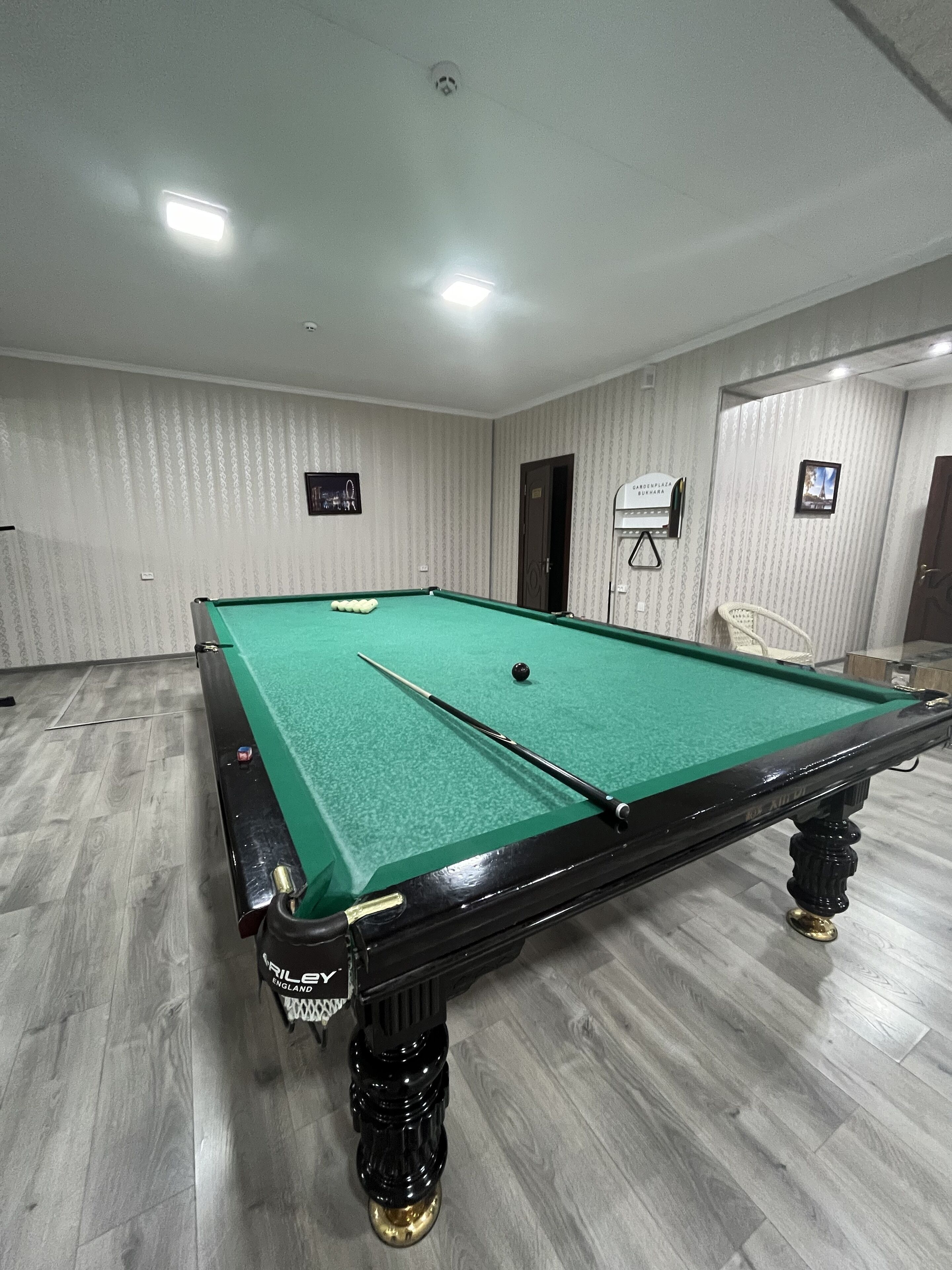 A pool table with balls, a cue stick, and a billiard rack.