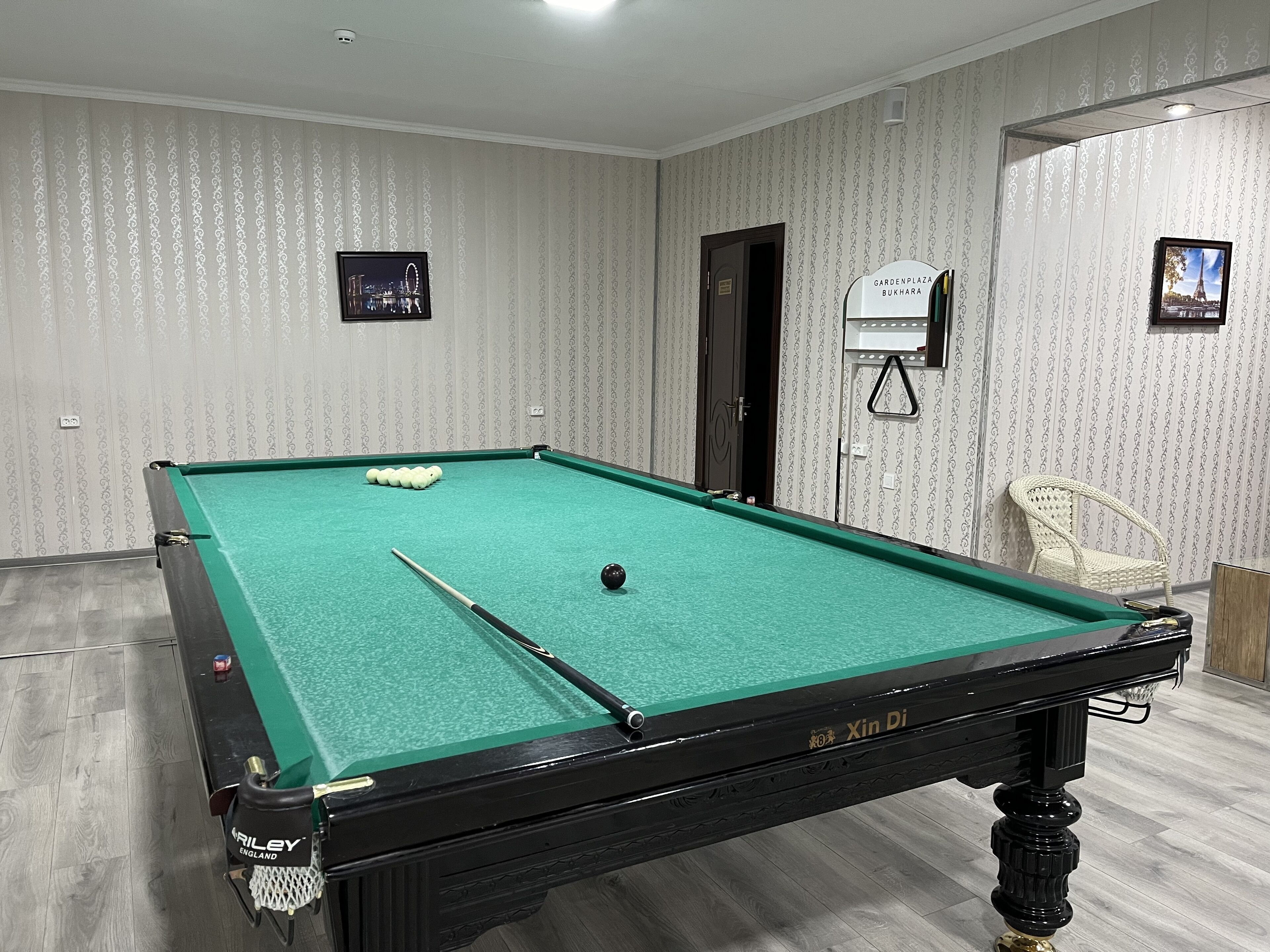 A pool table with a green felt surface, a pool cue, and several billiard balls.
