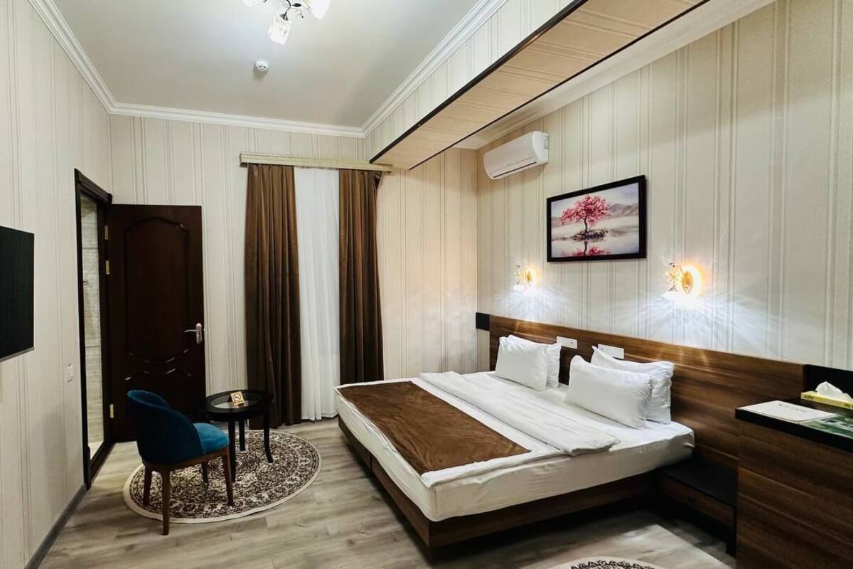 Ein Hotelzimmer mit Bett, Fernseher, Schreibtisch, Stuhl und einem Bild an der Wand.
