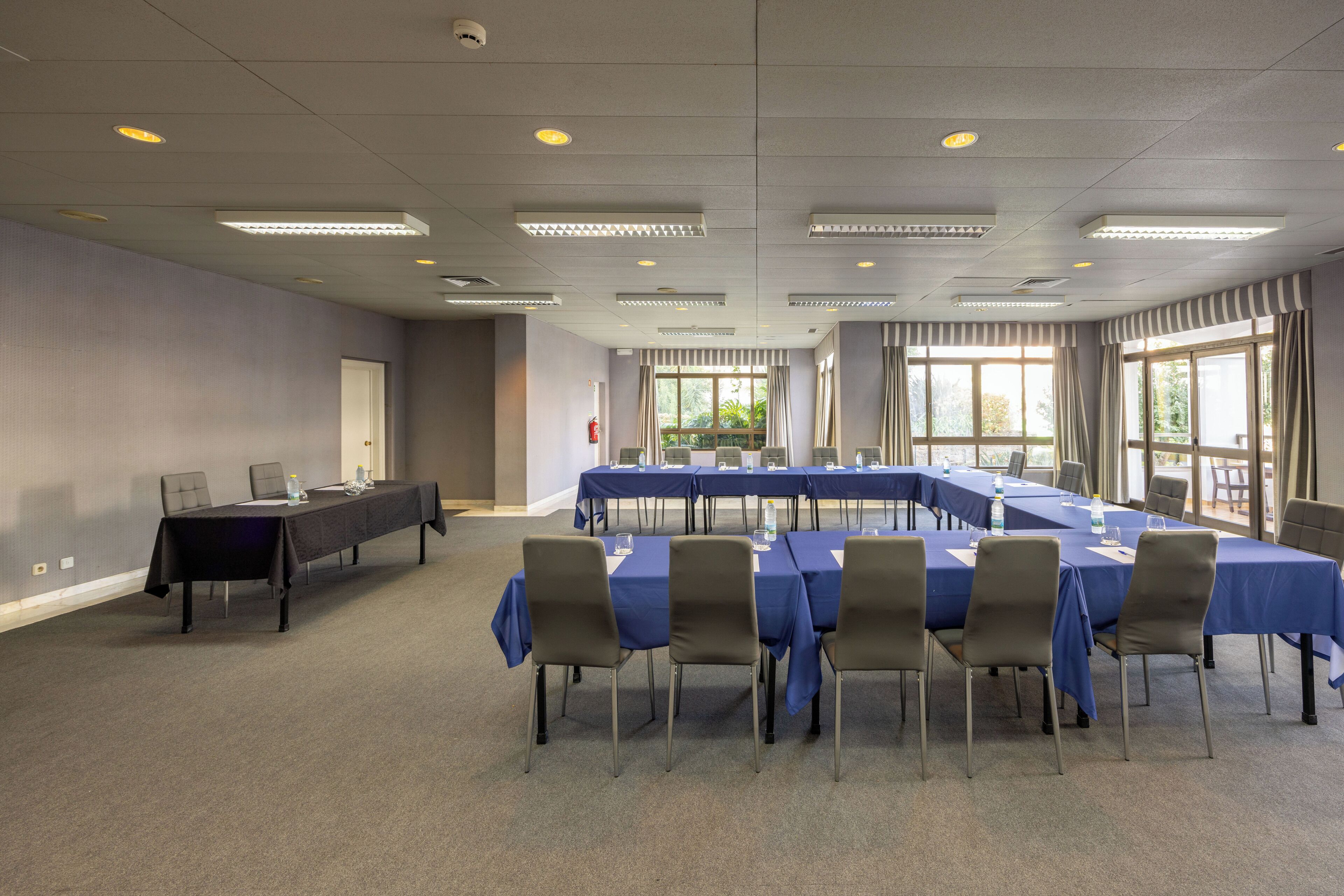 A conference room with a long table, chairs, and a carpeted floor.