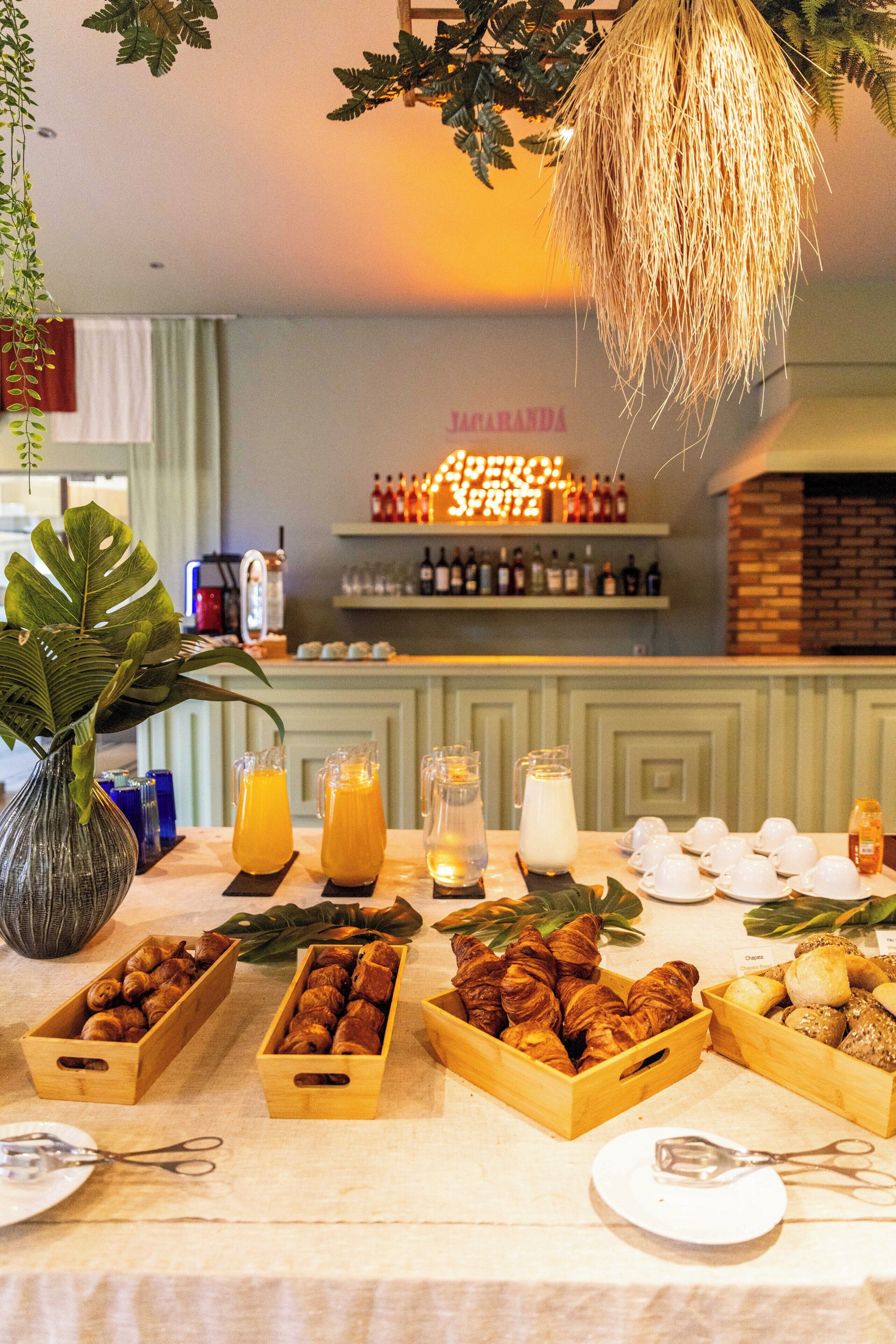 A breakfast buffet with various pastries, drinks, and a plant.