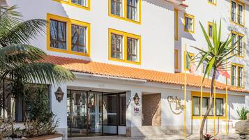 A white building with yellow trim and a tiled roof, featuring a sign that reads "Clube Lago."