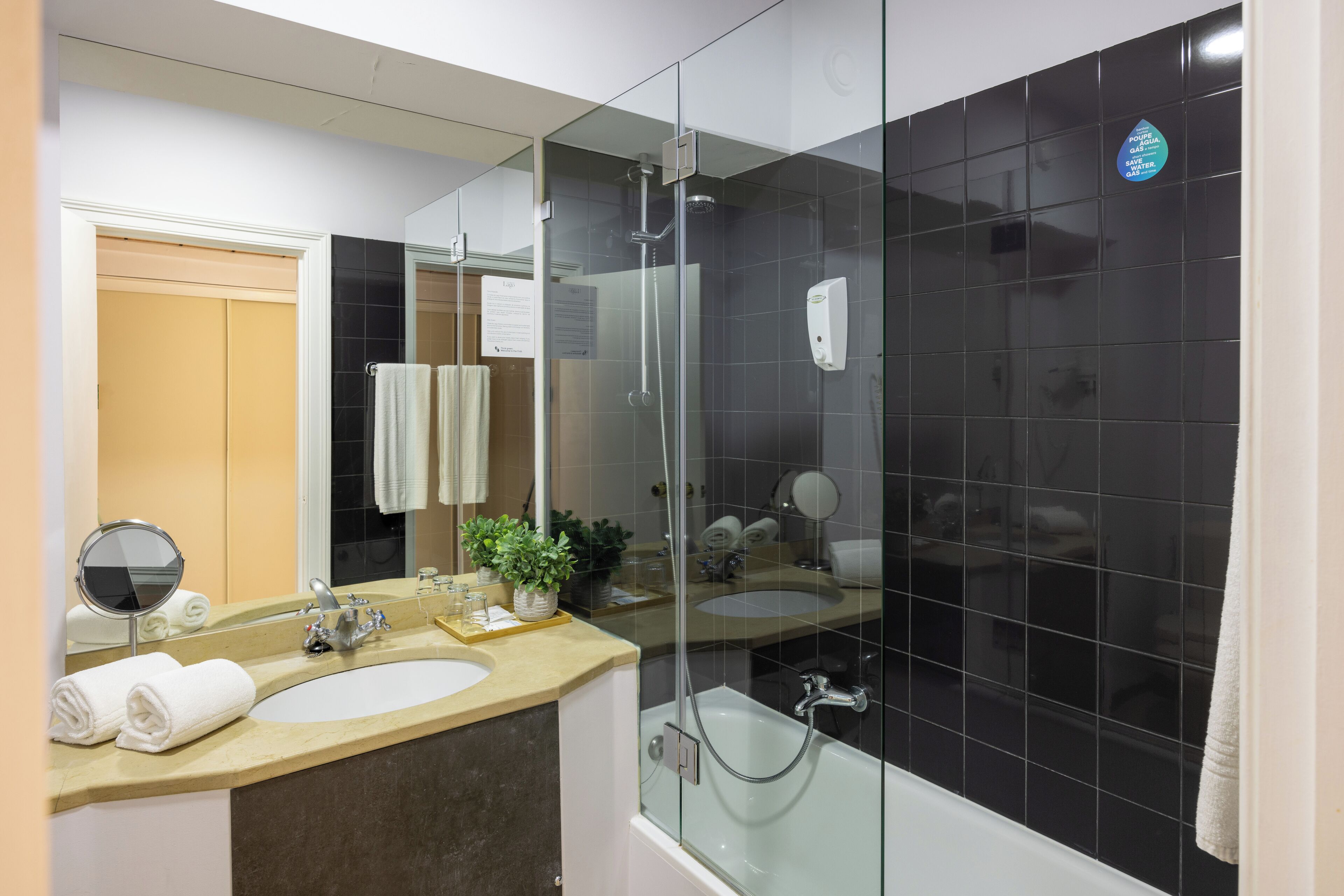 Un baño moderno con ducha envuelta en vidrio, un lavamanos y un espejo.