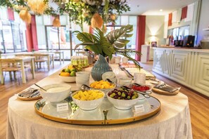 Una mesa de buffet con diversos alimentos y una planta decorativa en el centro.
