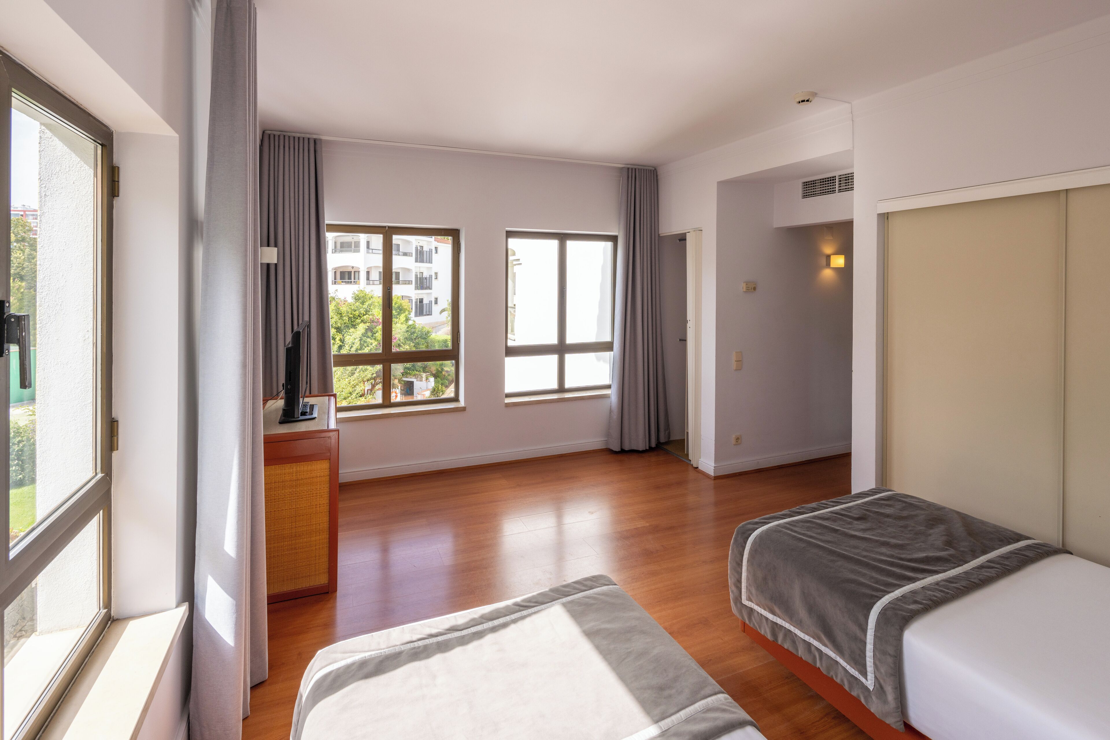 Una camera d'albergo moderna con una grande finestra, un letto, una TV e una piccola scrivania.