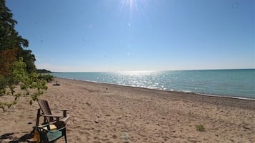 Relax in a tranquil beach setting with a comfortable chair on the sand, steps from the ocean.