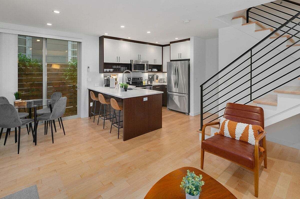 A modern kitchen with a central island, stainless steel appliances, and a dining area with a table and chairs.