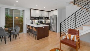 Una cocina moderna con una isla central, electrodomésticos de acero inoxidable y un comedor con mesa y sillas.