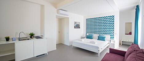 Un dormitorio moderno y minimalista con cama, mesita de noche, cómoda y un amplio ventanal.