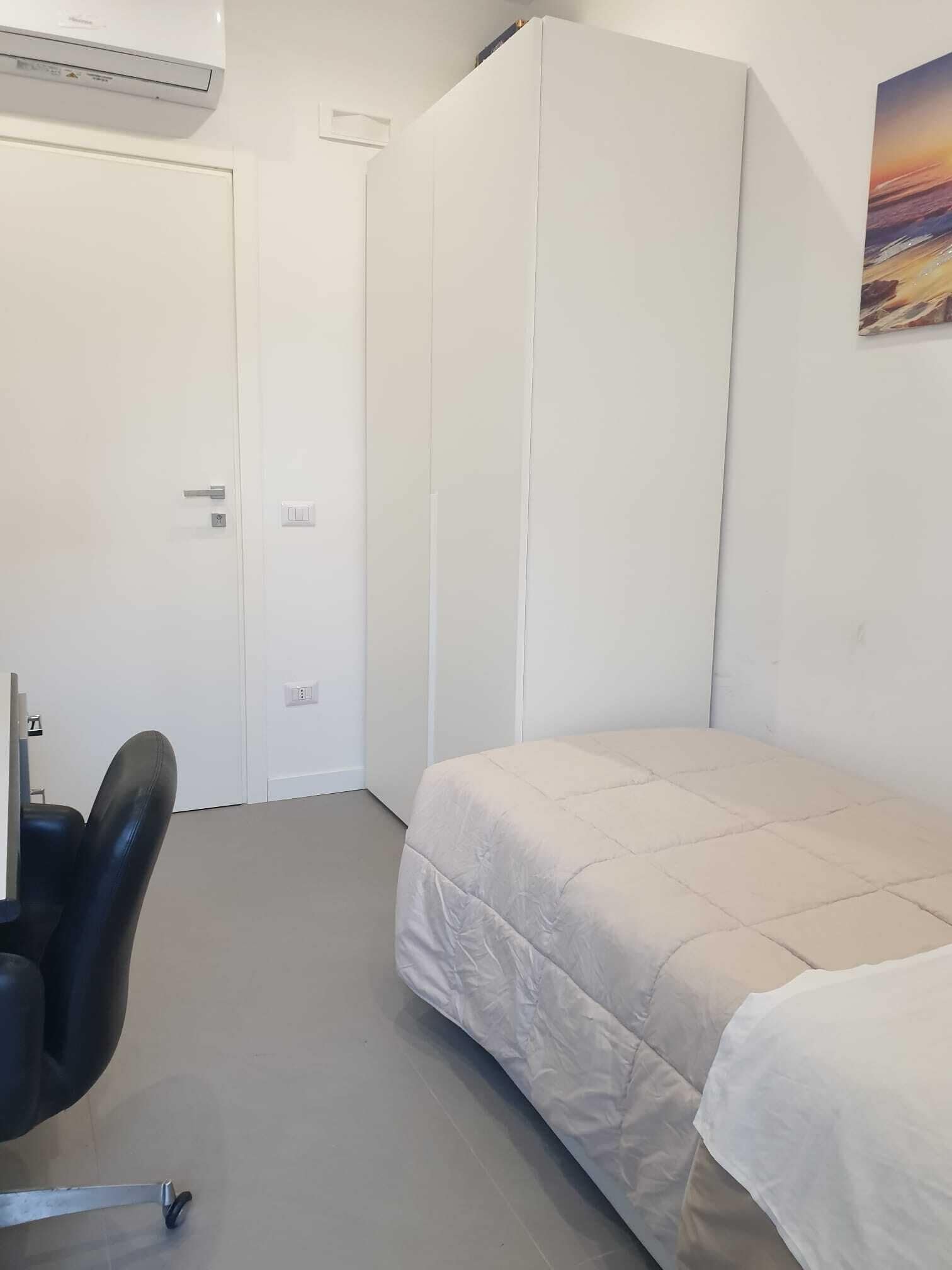 Una camera da letto con un letto, una scrivania e un condizionatore d'aria.