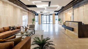 Un vestíbulo moderno con mostrador de recepción, sofás de cuero, una mesa de centro y una planta grande.