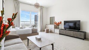 Una habitación de hotel moderna con una cama grande, televisor, sofá y zona de comedor.