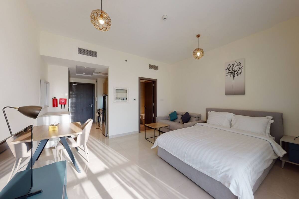 Een moderne hotelkamer met een groot bed, een bureau met stoel, een bank en twee hanglampen.