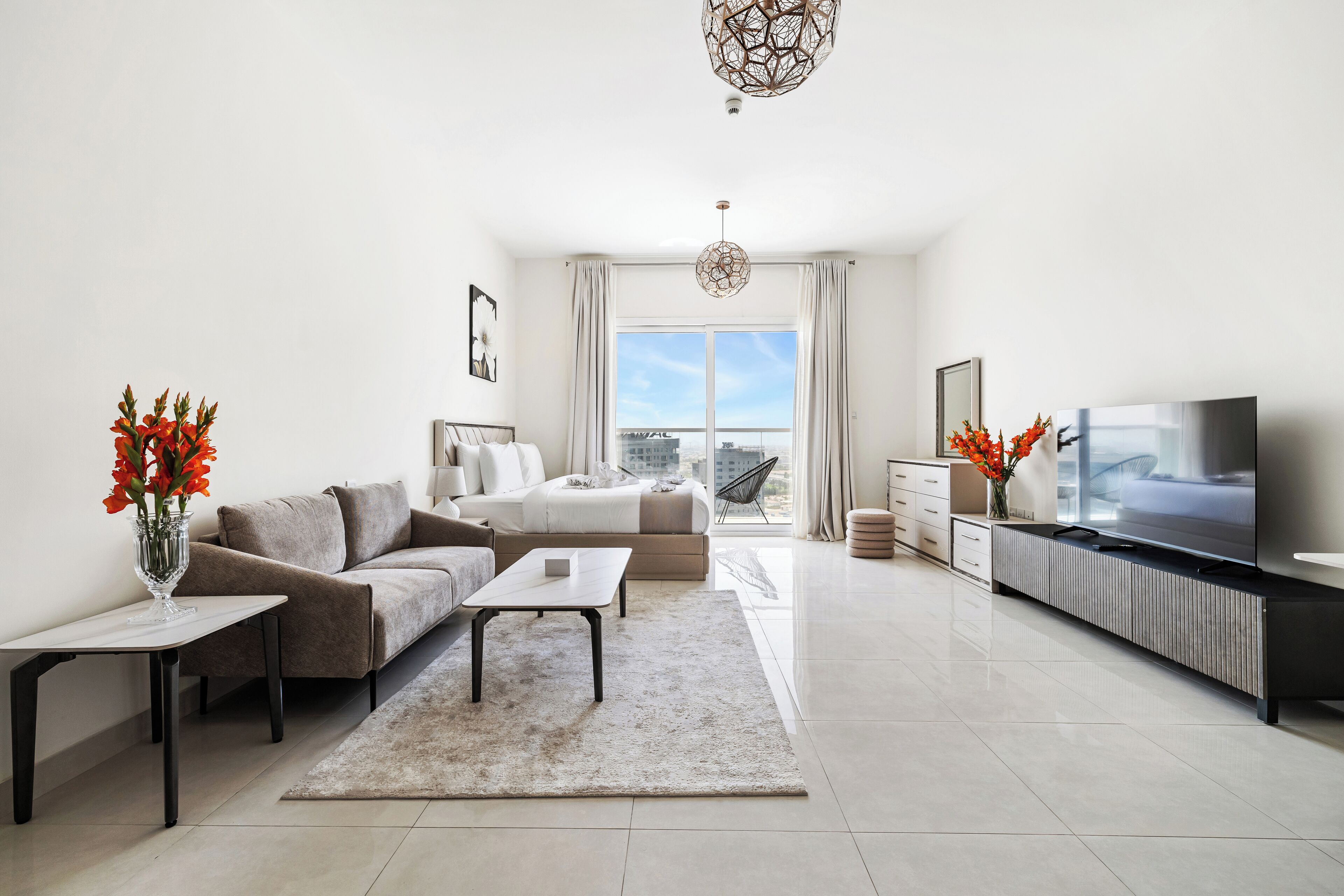 A modern living room with a sofa, coffee table, TV, and decorative vases.