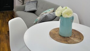 A modern living room with a grey sofa, white chairs, a round white table with a wooden coaster, and a vase with white flowers. - Santa Marta Apartment by Trip2Portugal (Lisbon)