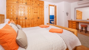 A bedroom with a large bed, wooden wardrobe, a mirror, and a small stool. - 3 Bedroom Family Villa in Javea (Javea / Xàbia)