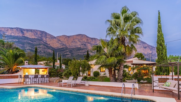 A swimming pool with lounge chairs, a bar, and a mountain backdrop. - 3 Bedroom Family Villa in Javea (Javea / Xàbia)
