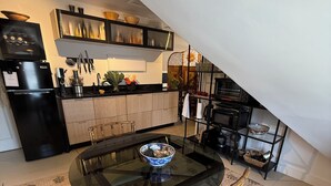 Una cucina compatta con zona pranzo, che include un frigorifero nero, un fornello e un forno a microonde.