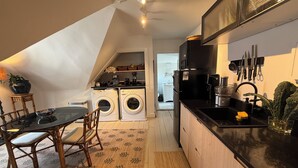 Una cucina compatta con zona pranzo, lavatrice e piano di lavoro nero.