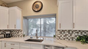 A kitchen with white cabinets, a stainless steel sink, a coffee maker, and a clock on the wall. - FANTASTIC Scottsdale location! Close to Waste Management Open, and Westworld!! (Scottsdale)