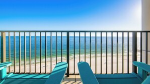 A balcony with a view of the ocean, two blue chairs, and a railing. - Oasis 1704 - Beach Front Elegance (Orange Beach)