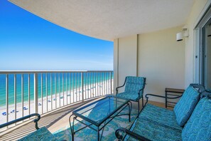 A balcony with a glass table and chairs, a view of the beach, and a clear blue sky. - Stunning 1BR Royal Palms Unit 1107 with Beautiful Gulf Front Views! (Gulf Shores)