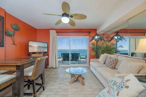 A room with a ceiling fan, a glass table, wicker chairs, a sofa, and a view of the ocean through a sliding glass door. - Stunning 1BR Royal Palms Unit 1107 with Beautiful Gulf Front Views! (Gulf Shores)