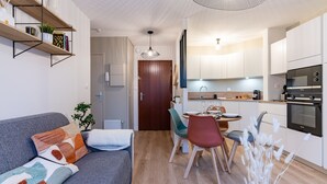Una cucina moderna con mobili bianchi, forno integrato e zona pranzo con tavolo e sedie.