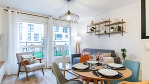 Un soggiorno moderno con zona pranzo, ampie finestre e vista su un edificio.