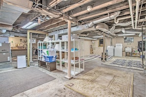 Exposed ceilings and ductwork define this industrial-style room with a central shelving unit and a small refrigerator.