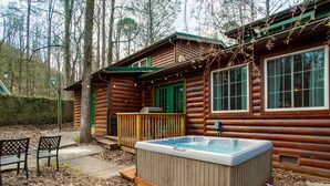 Una cabaña con jacuzzi, terraza de madera y dos sillas.