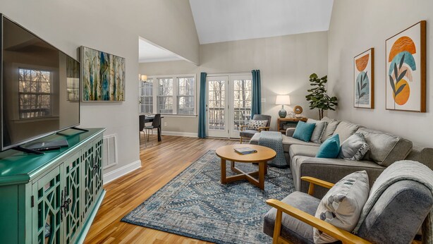 A spacious living room with a large TV, comfortable seating, a coffee table, and artwork on the walls. - Near downtown Cary & RDU. Easy access to Raleigh, Durham and local venues. (Cary)
