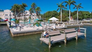A waterfront hotel with a pool area, palm trees, and a dock. - PALM BAY 5th floor ON THE BEACH 
Sunsets from the open lanai, Two Queen beds.  (Sarasota)
