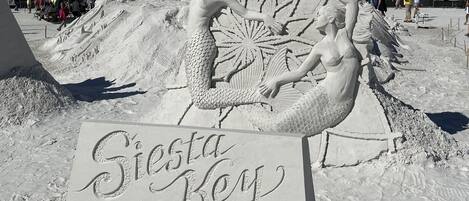 A sand sculpture of mermaids with a sign reading "Siesta Key".