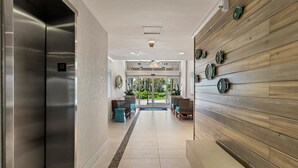A modern hotel lobby with a reception desk, seating area, and a view of the outdoors. - PALM BAY 5th floor ON THE BEACH 
Sunsets from the open lanai, Two Queen beds.  (Sarasota)