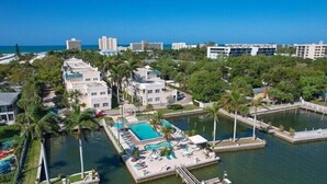 An aerial view of a resort with multiple buildings, a central pool area, and a marina. - PALM BAY 5th floor ON THE BEACH 
Sunsets from the open lanai, Two Queen beds.  (Sarasota)