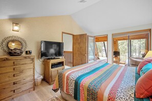 Une chambre avec un grand lit, une commode en bois, une télévision et une vue sur l’extérieur.