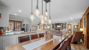 A spacious kitchen with a large island, pendant lighting, and a dining area with a wooden table and chairs.