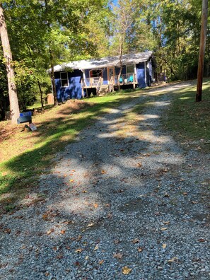 A gravel path leading to a row of cabins with a wooden deck and a blue building in the background. - Lovely Bungalow in private , secluded neighborhood near Carrboro (Chapel Hill)