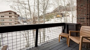 A balcony with a view of a snowy landscape, a brick wall, and a wooden bench.