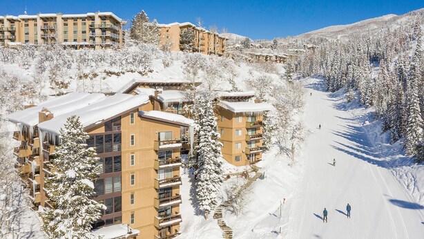 A snow-covered ski resort with multi-story buildings, ski slopes, and snow-covered trees.