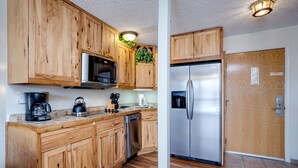 A kitchen with wooden cabinets, a stainless steel refrigerator, a microwave, and a coffee maker.