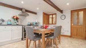 A kitchen with a dining table, chairs, a microwave, and a stove. - Water Wheels@the West Dry (St Austell)