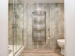 Une salle de bain avec une douche à parois de verre, un porte-serviettes fixé au mur et des toilettes.