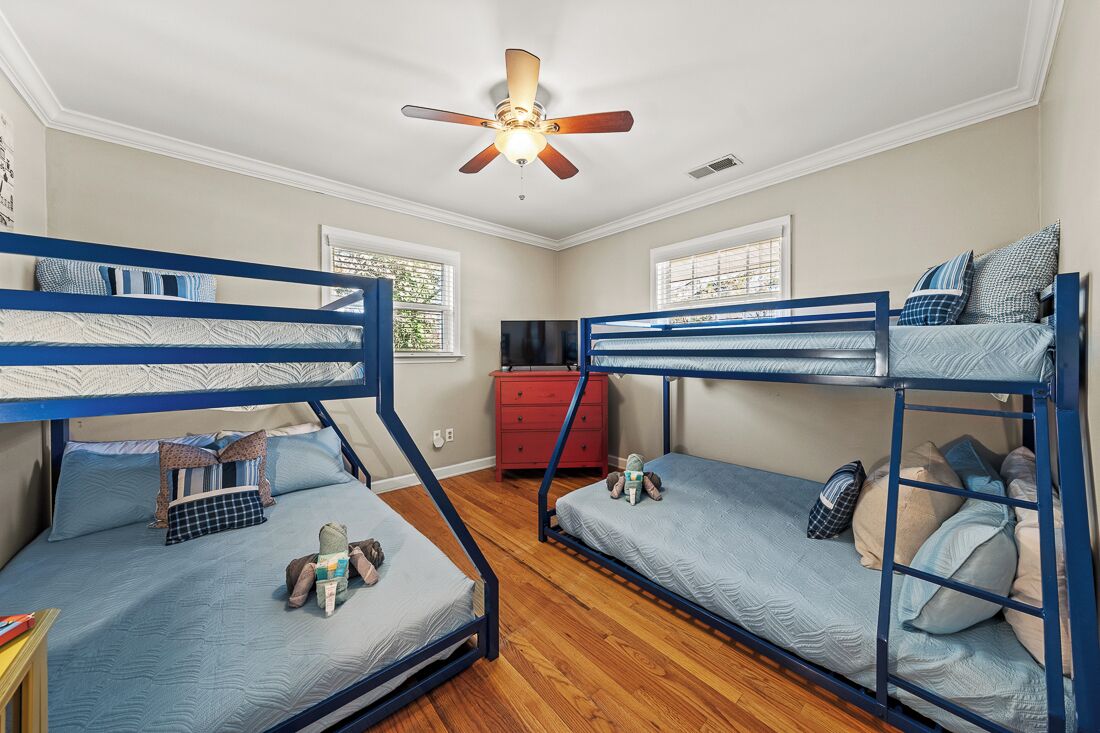 A room with bunk beds, a ceiling fan, and a red dresser.