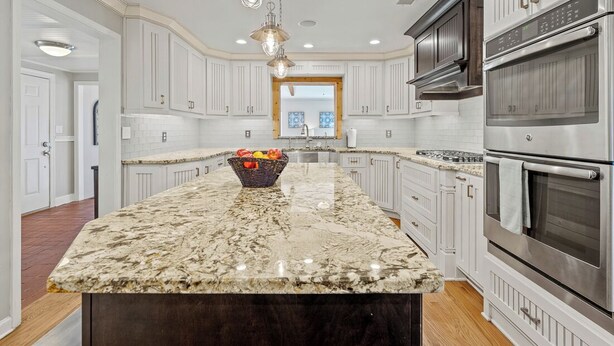 A kitchen with white cabinets, a granite countertop, stainless steel appliances, and pendant lighting. - Much to love Guest favorite Evergreen Hideaway waterfront home w/ dock. Pets ok (Gainesville)