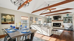 A spacious living room with a fireplace, a dining area with a table set for four, and a cozy seating area with a sofa and armchairs. - Much to love Guest favorite Evergreen Hideaway waterfront home w/ dock. Pets ok (Gainesville)