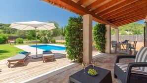 A covered outdoor area with a pool, lounge chairs, a table with drinks, and a view of the surrounding greenery. - Vista Verde by Balearic Villas (Pollensa)